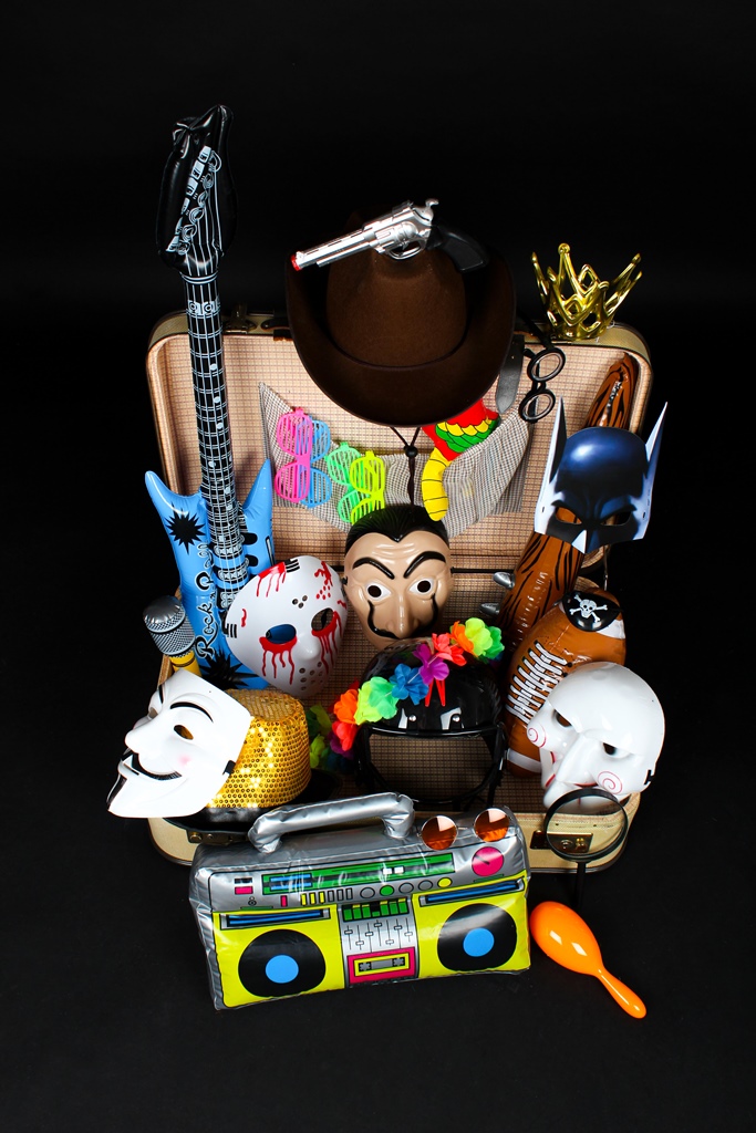 Koffer mit Verkleidungsdingen wie Masken, Hüten, Partybrillen und aufblasbarem Radio sowie Gitarre.